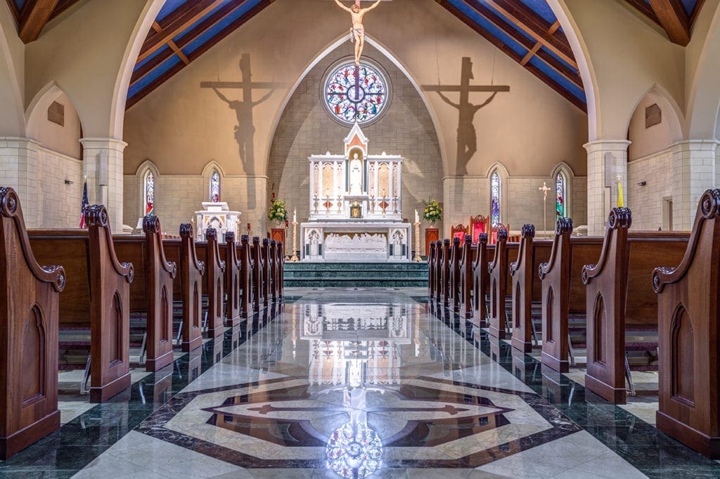 Interior of St. Peter Chanel Church showing rows of wooden pews and a white altar.