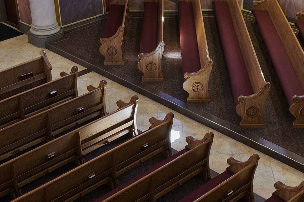 An aerial view of straight church pews, with red cushioned seats.